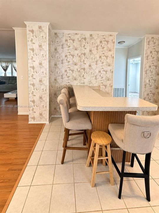 Built-in bar with a solid surface countertop, wood-paneled cabinetry, and ceramic tile flooring