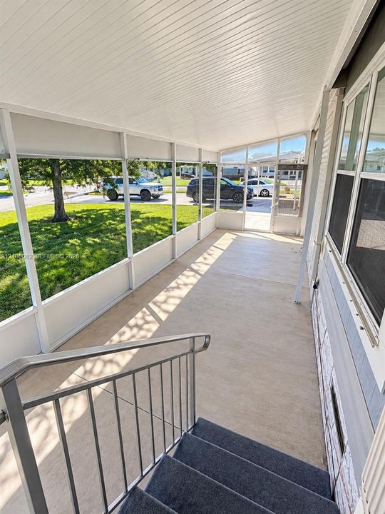 Screened-in porch featuring a concrete floor, white aluminum framing, beadboard ceiling, and metal handrail