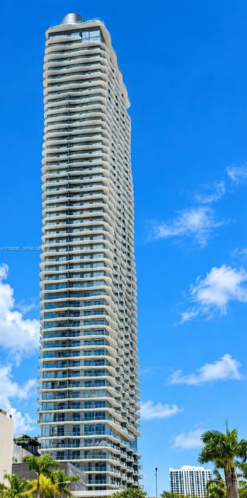 High-rise architecture featuring a glass facade, undulating balcony balconies, and a reinforced concrete structure