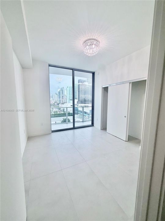 Floor-to-ceiling sliding glass doors, large-format tile flooring, crystal-accented flush mount lighting, and a sliding door closet