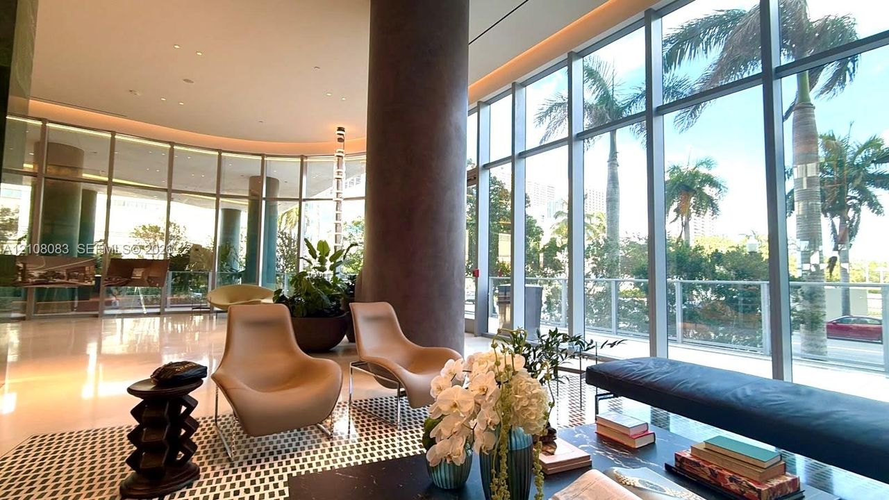 Floor-to-ceiling glass curtain walls, expansive polished stone flooring, recessed ceiling lighting, and prominent cylindrical architectural columns