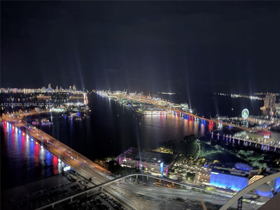 Elevated perspective of the metropolitan shoreline, bridges, and harbor featuring distinct urban lighting