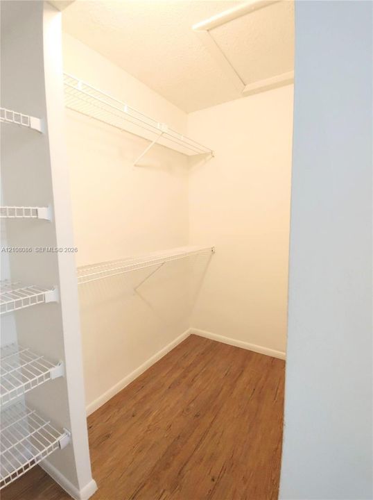 Storage space featuring wood-finish flooring and white wire shelving units