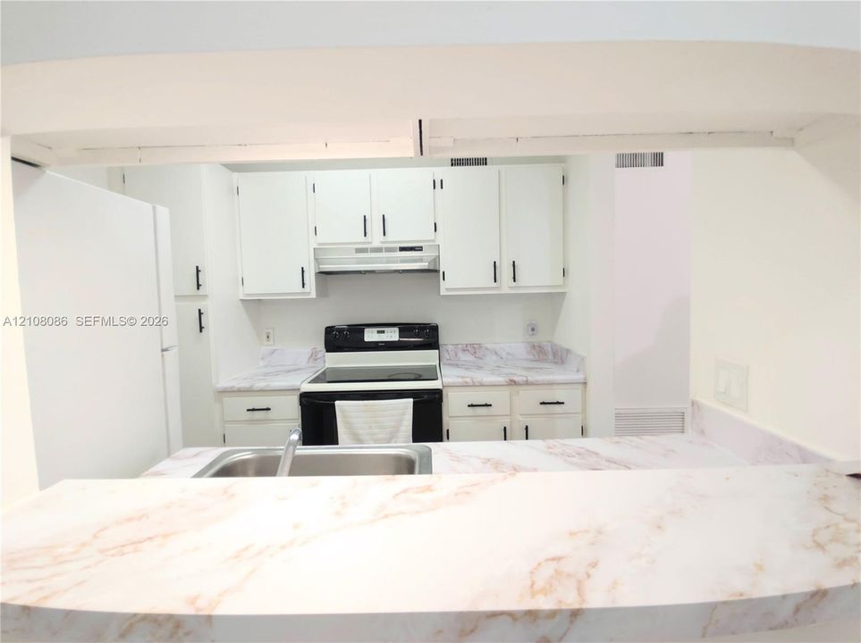 Kitchen featuring white cabinetry with matte black hardware, stone-finish countertops, stainless steel sink, and electric range
