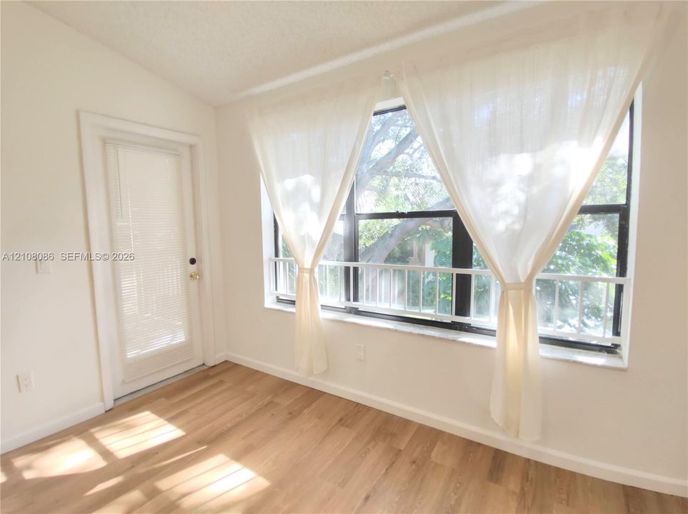 Large windows featuring natural light, wood-finish flooring, and a glass-paneled entry door