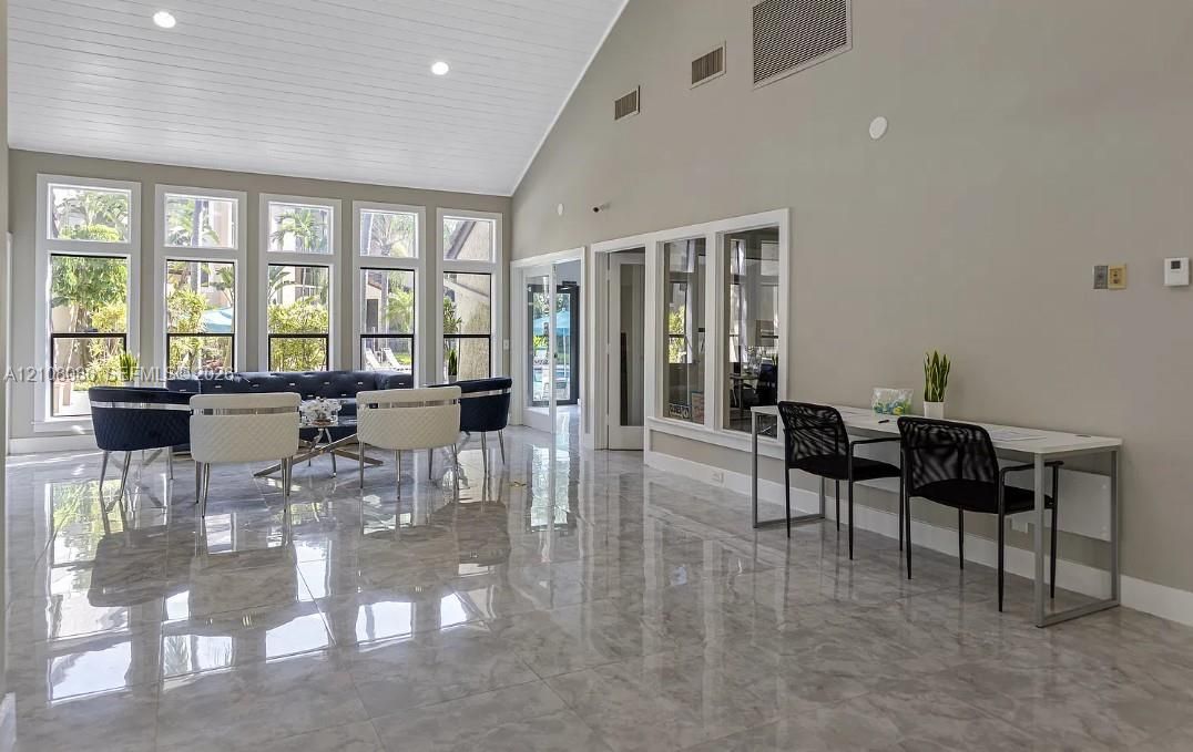 Vaulted ceiling with tongue-and-groove paneling, polished stone-finish tile flooring, and floor-to-ceiling windows