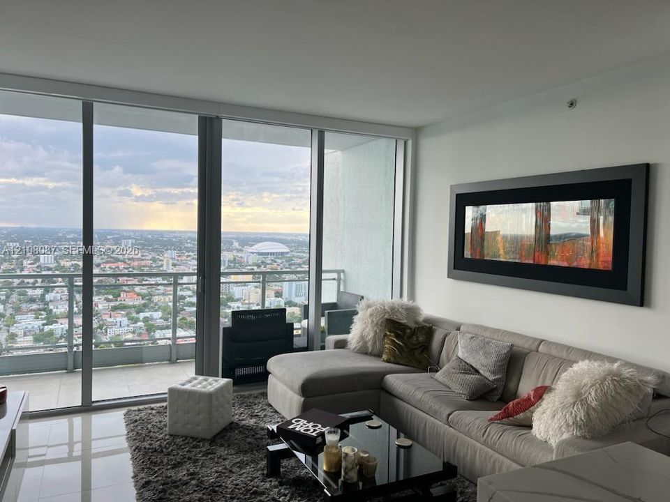 Floor-to-ceiling windows, aluminum-frame sliding glass door, private balcony, and tile flooring