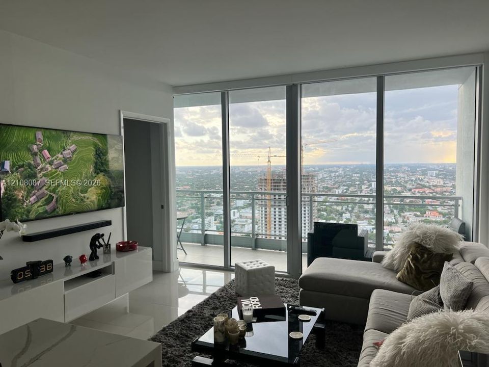 Floor-to-ceiling windows, private balcony with metal railing, and high-gloss white built-in cabinetry