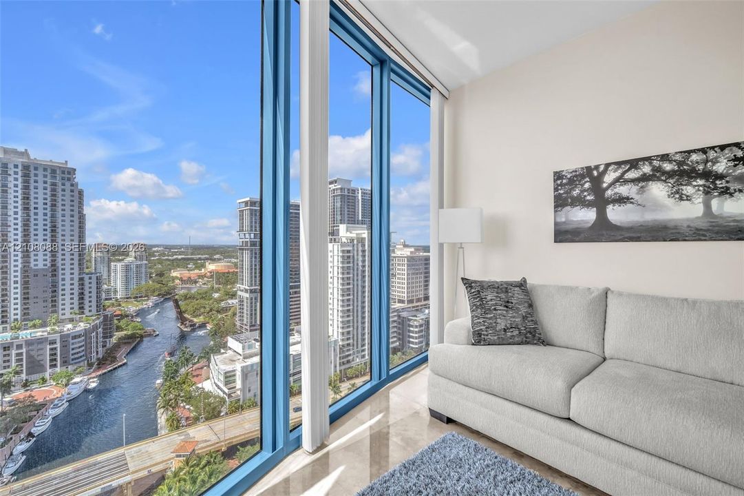 Guest Bedroom set up as den or media room. Floor-to-ceiling windows featuring panoramic urban scenery and polished tile flooring