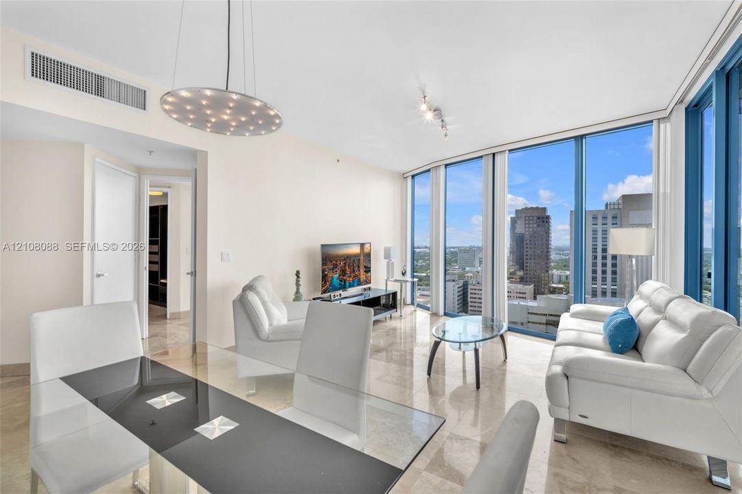 Open-concept interior featuring floor-to-ceiling windows, natural stone flooring, and a decorative disc-style pendant light