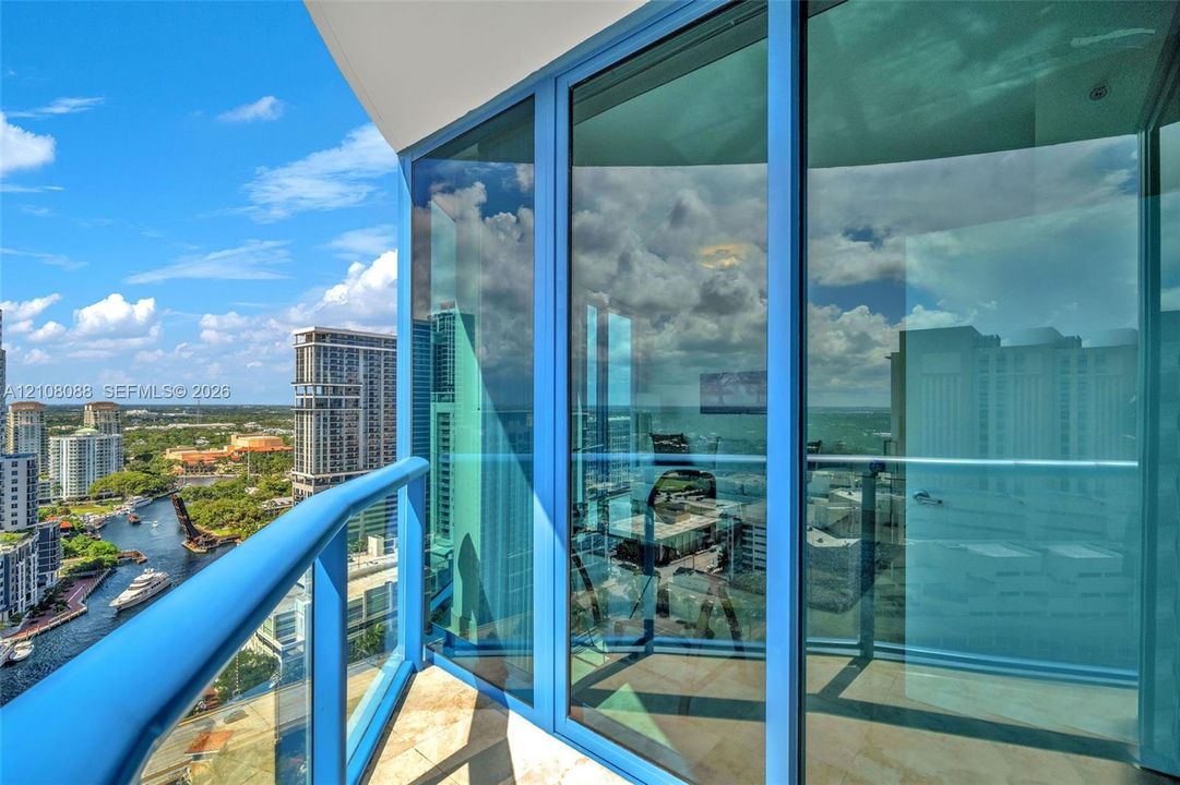 Direct New River views. Private balcony featuring floor-to-ceiling glass paneling, metal railings, and stone-tile flooring