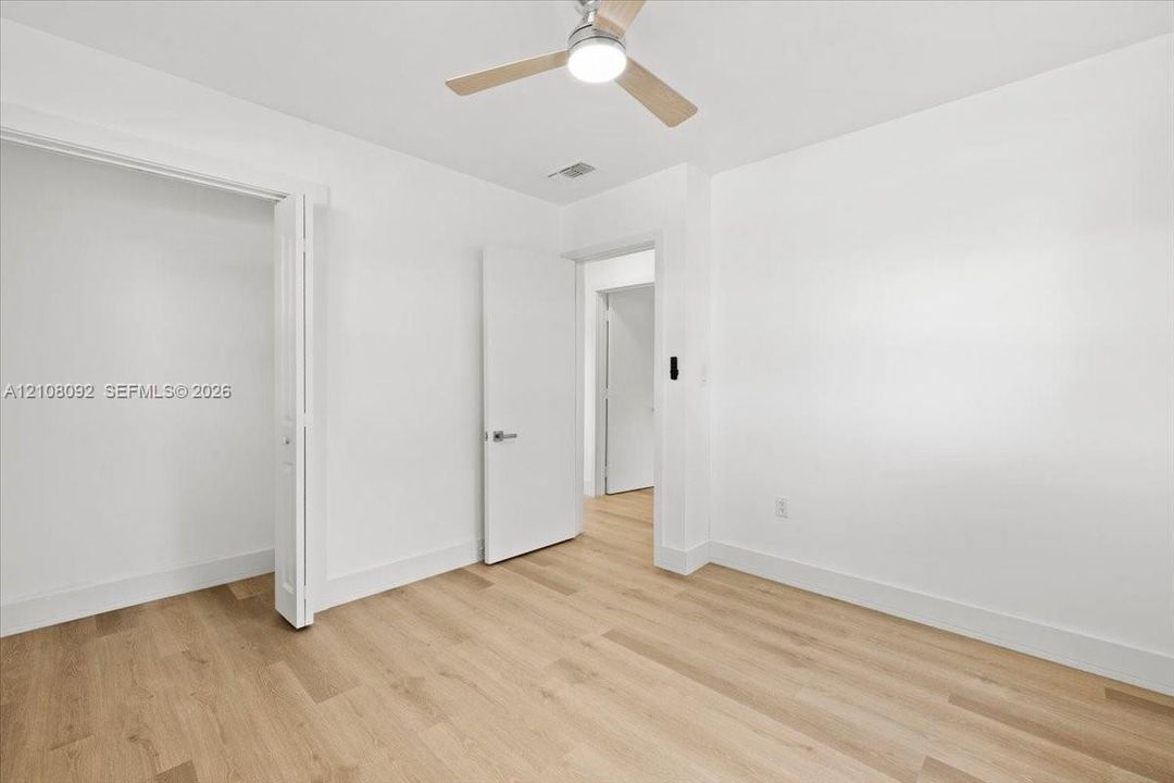 Room featuring wood-finish flooring, a ceiling fan with integrated lighting, and a bifold closet door