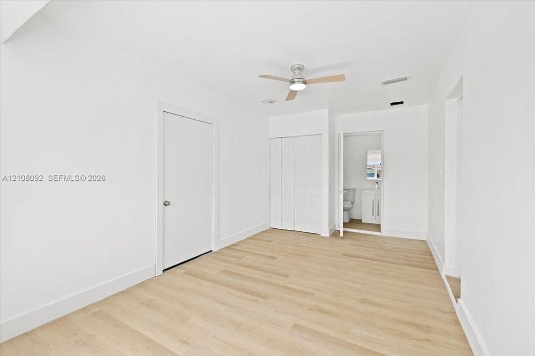 Room featuring wood-finish flooring, a neutral color palette, ceiling fan with integrated lighting, and white six-panel doors