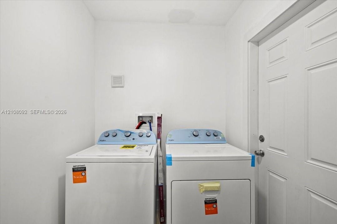 Dedicated laundry area featuring a white six-panel door and plumbing hookups for a top-load washer and dryer