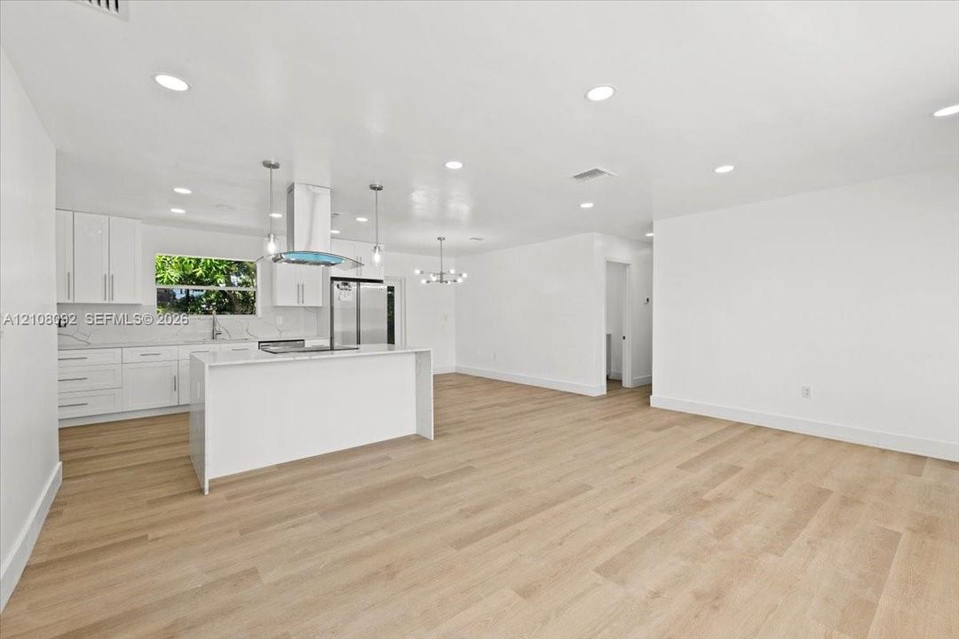 Kitchen featuring white cabinetry, solid-surface countertops, wood-finish flooring, recessed lighting, and a stainless steel range hood
