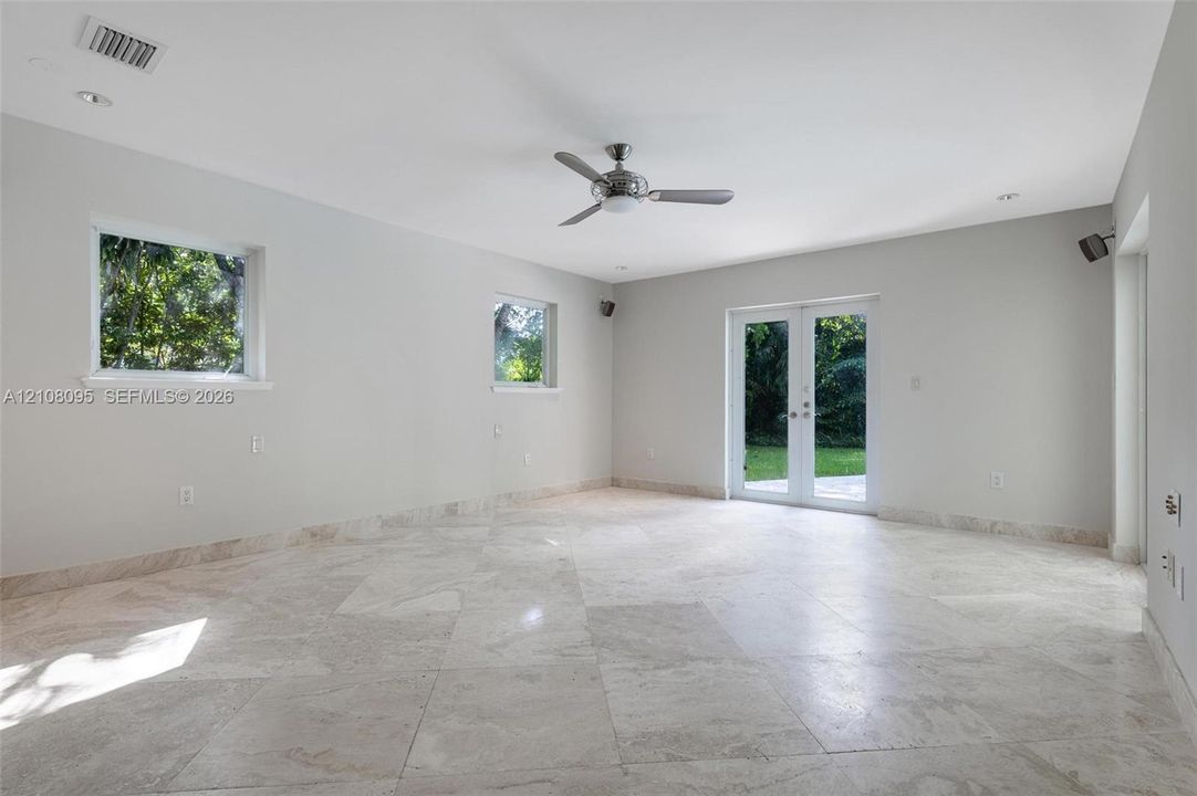 Interior space featuring large-format stone flooring, recessed lighting, a ceiling fan, dual windows, and glass-paned double doors