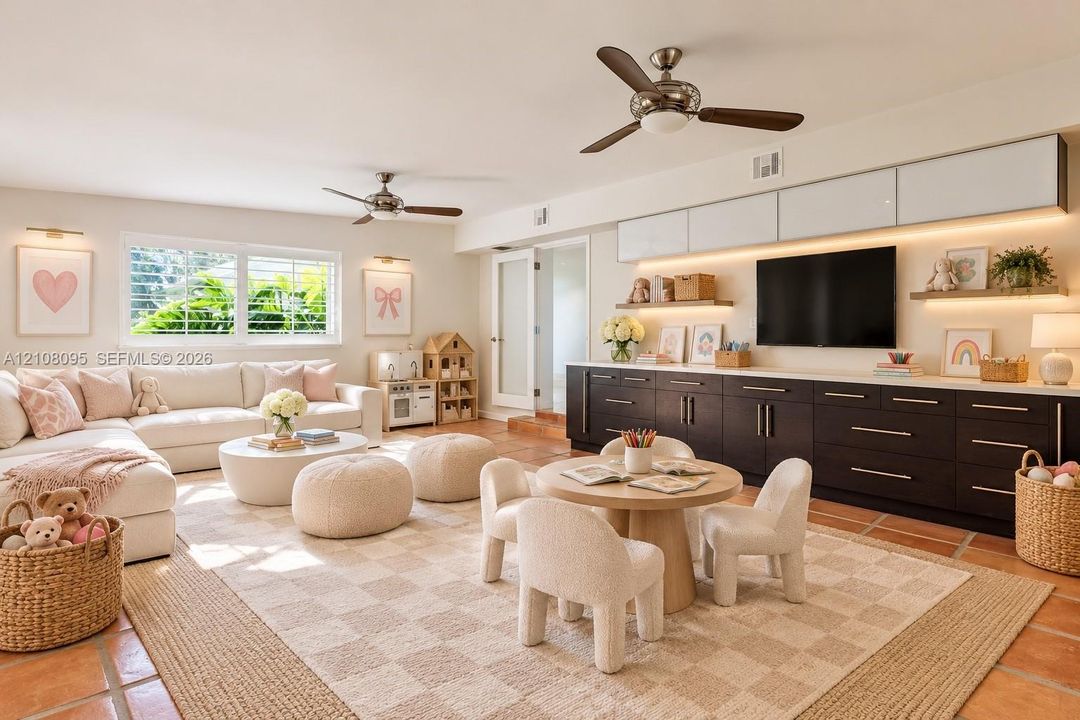Living area featuring custom dark cabinetry with integrated lighting, wall-mounted upper storage, multi-toned tile flooring, and dual ceiling fans
