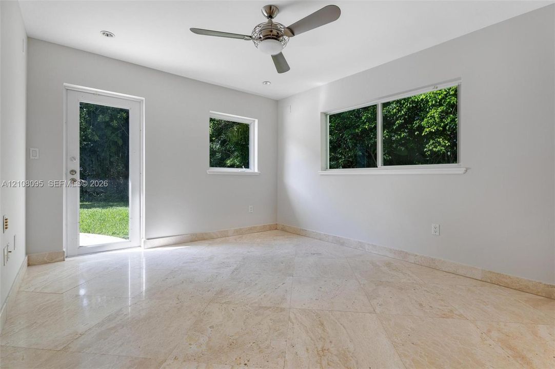 Neutral-toned interior featuring large-format tile flooring, recessed ceiling lighting, a brushed-nickel ceiling fan, dual-pane windows, and a glass-panel exterior door