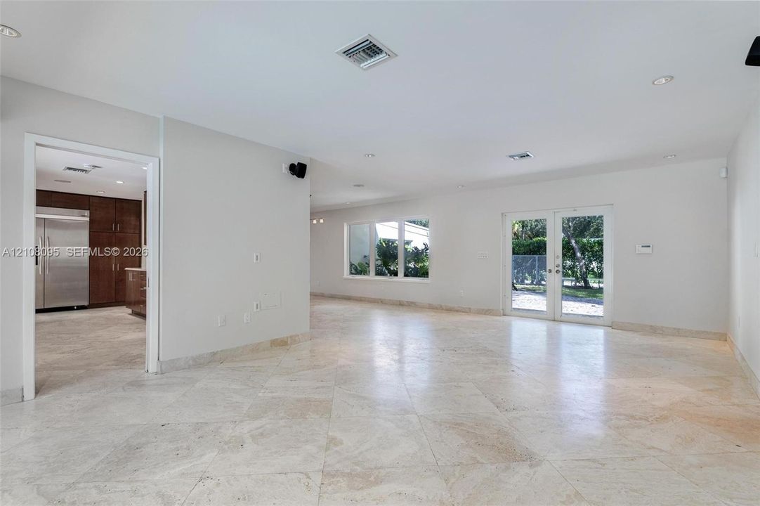 Open-concept interior featuring large-format stone tile flooring, recessed lighting, multi-pane windows, and glass-paned double doors