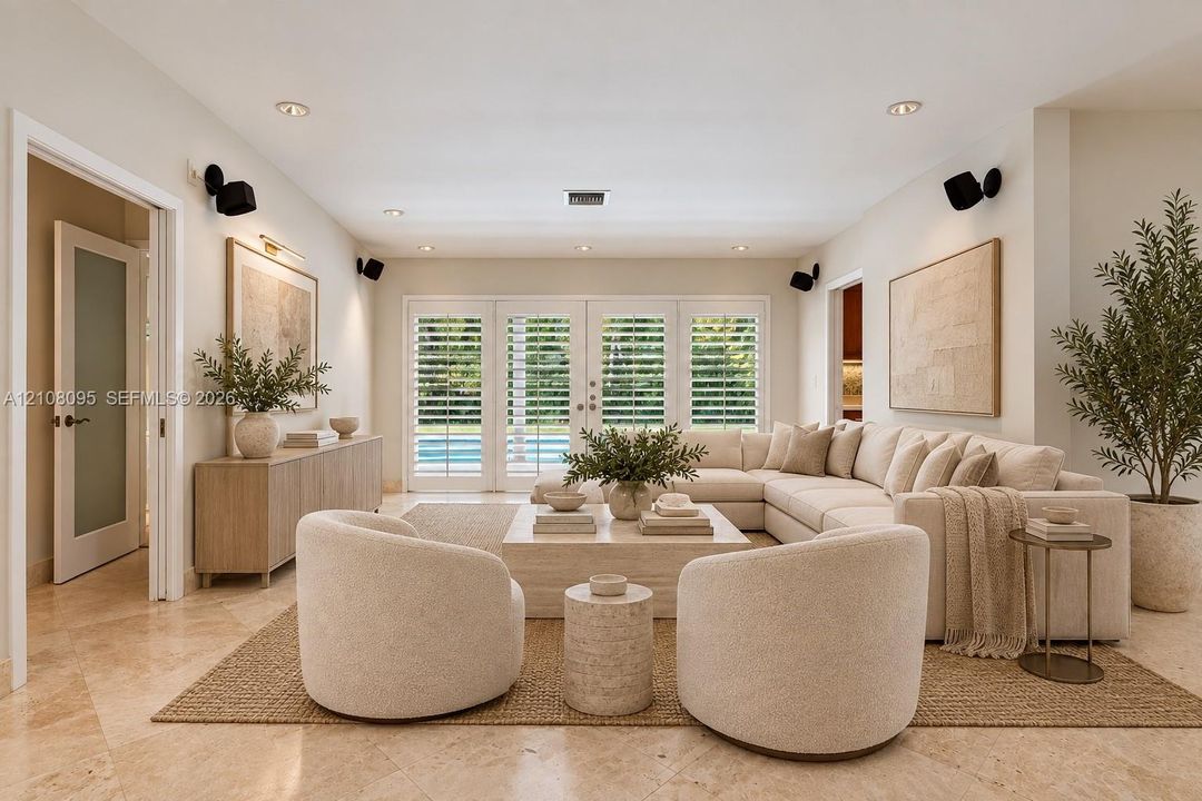 Living area featuring stone tile flooring, recessed lighting, wall-mounted speakers, and French doors with integrated shutters