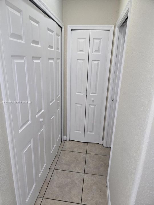 Neutral-toned ceramic tile flooring paired with white multi-panel bi-fold closet doors