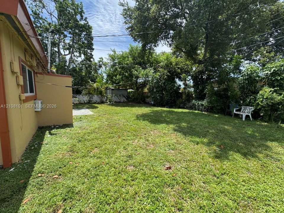 Expansive backyard featuring a lawn, perimeter fencing, and mature trees