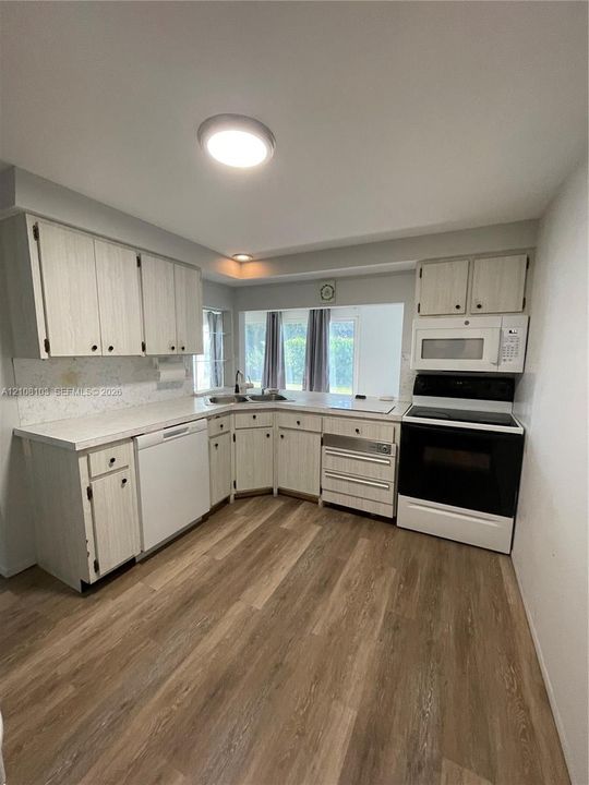 Kitchen featuring wood-finish flooring, white cabinetry, solid-surface countertops, and built-in appliances