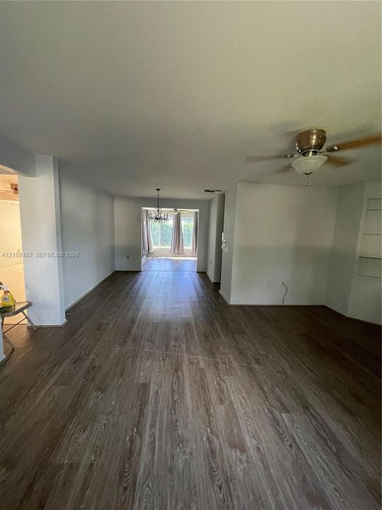 Open-concept interior featuring wood-finish flooring, recessed lighting, a ceiling fan with integrated light fixture, and built-in shelving