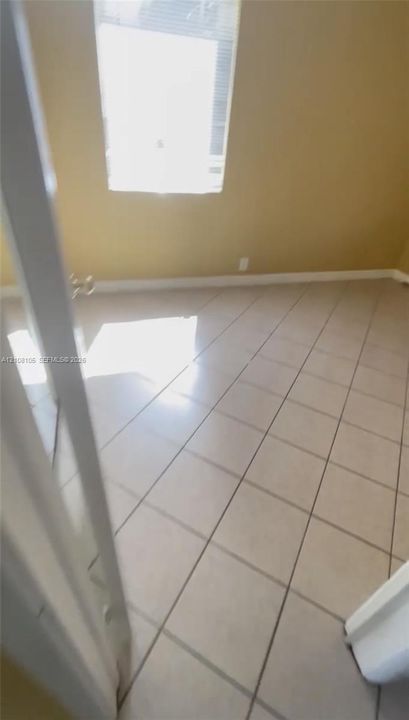 Neutral-toned ceramic tile flooring and a single window with horizontal blinds