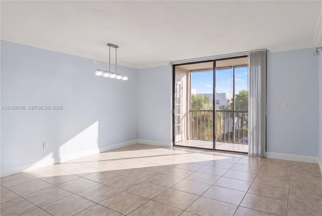 Ceramic tile flooring, crown molding, multi-light linear chandelier, and sliding glass door with access to a screened balcony