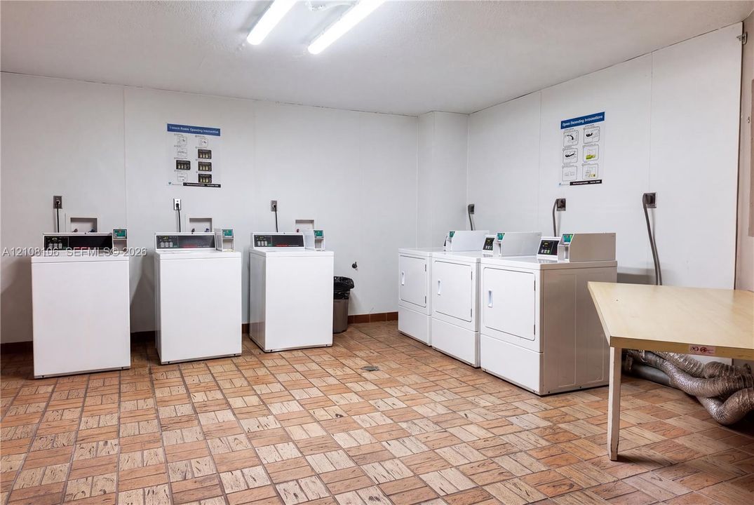 Laundry room featuring six coin-operated appliances, tile flooring, and a dedicated folding surface