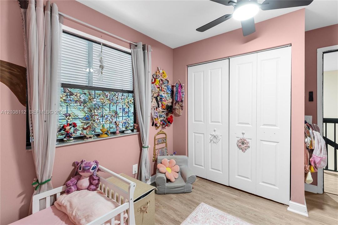 Room featuring wood-finish flooring, a double-door reach-in closet, and a ceiling fan with integrated lighting
