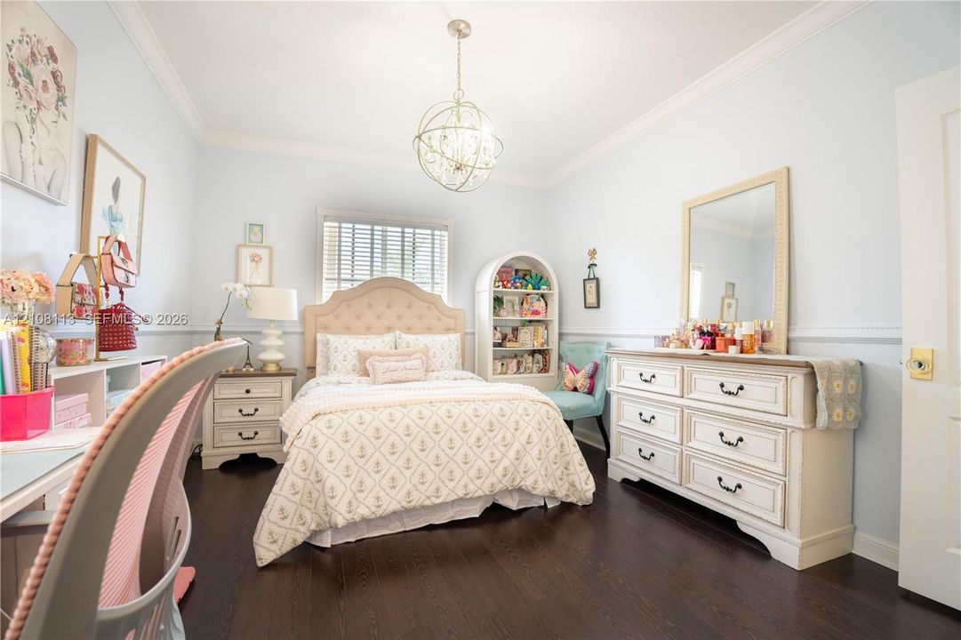 Room featuring dark wood-finish flooring, crown molding, chair rail trim, and a decorative orb-style chandelier