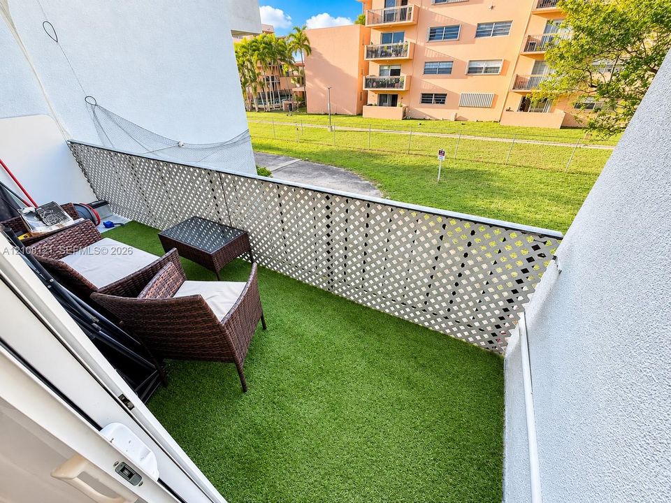 Private balcony featuring artificial turf flooring and white lattice privacy screening