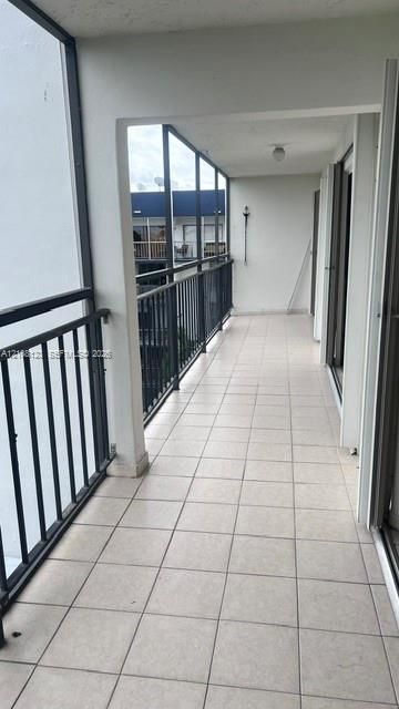 Covered balcony featuring square tile flooring and black metal railing
