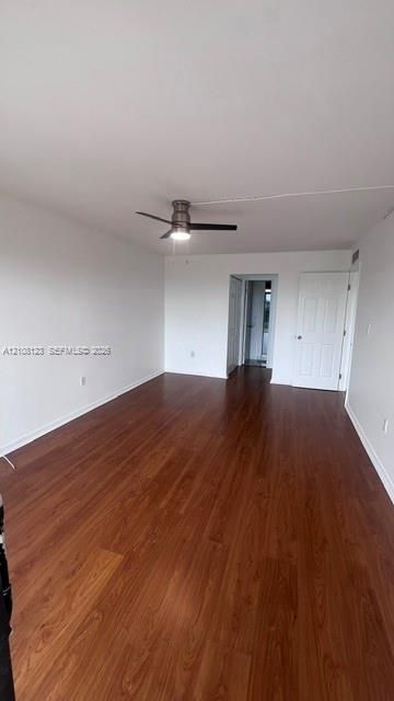 Interior space featuring wood-finish flooring, a ceiling fan with integrated lighting, and white six-panel interior doors