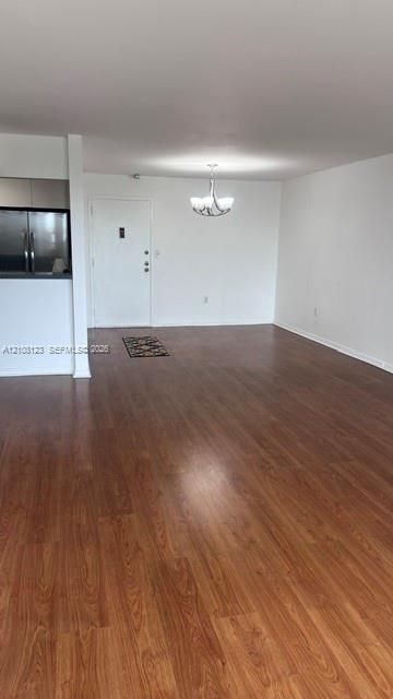 Open living area featuring wood-finish flooring, a multi-arm metallic chandelier, and neutral wall tones