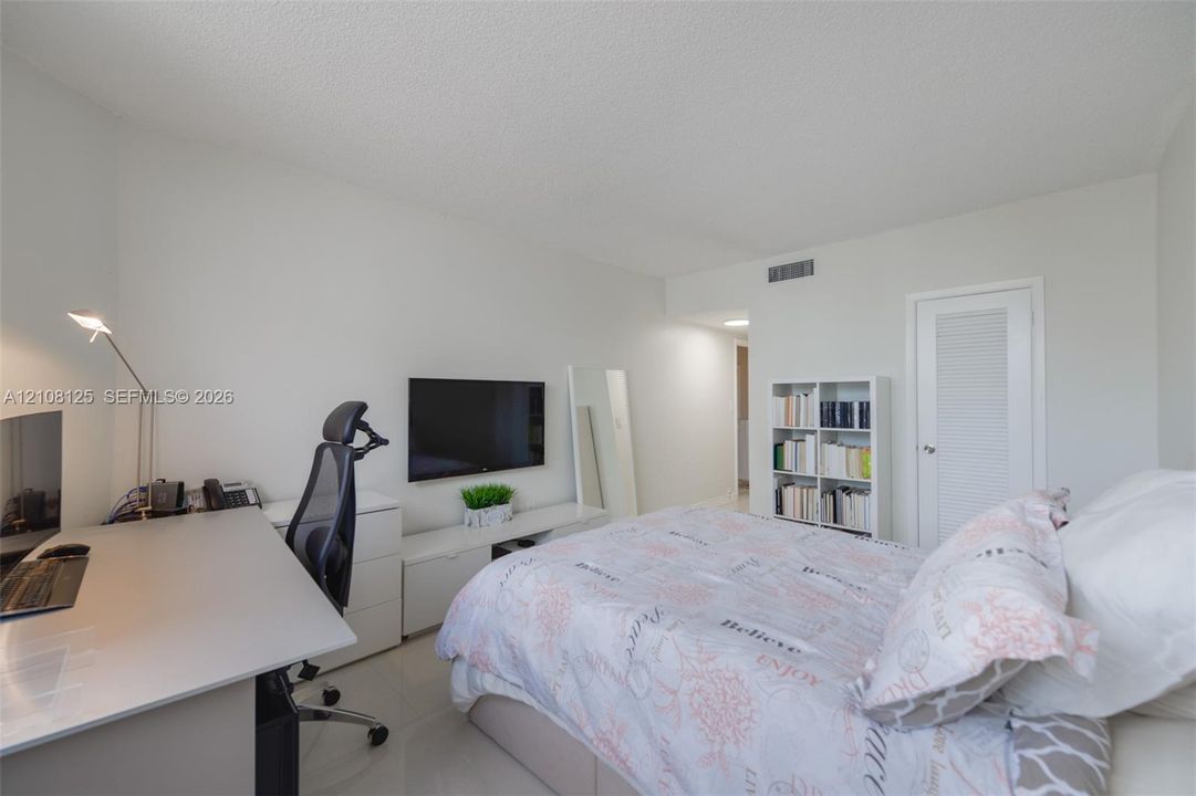 Neutral interior room featuring white walls, tile flooring, and a single-panel door with a louvered detail