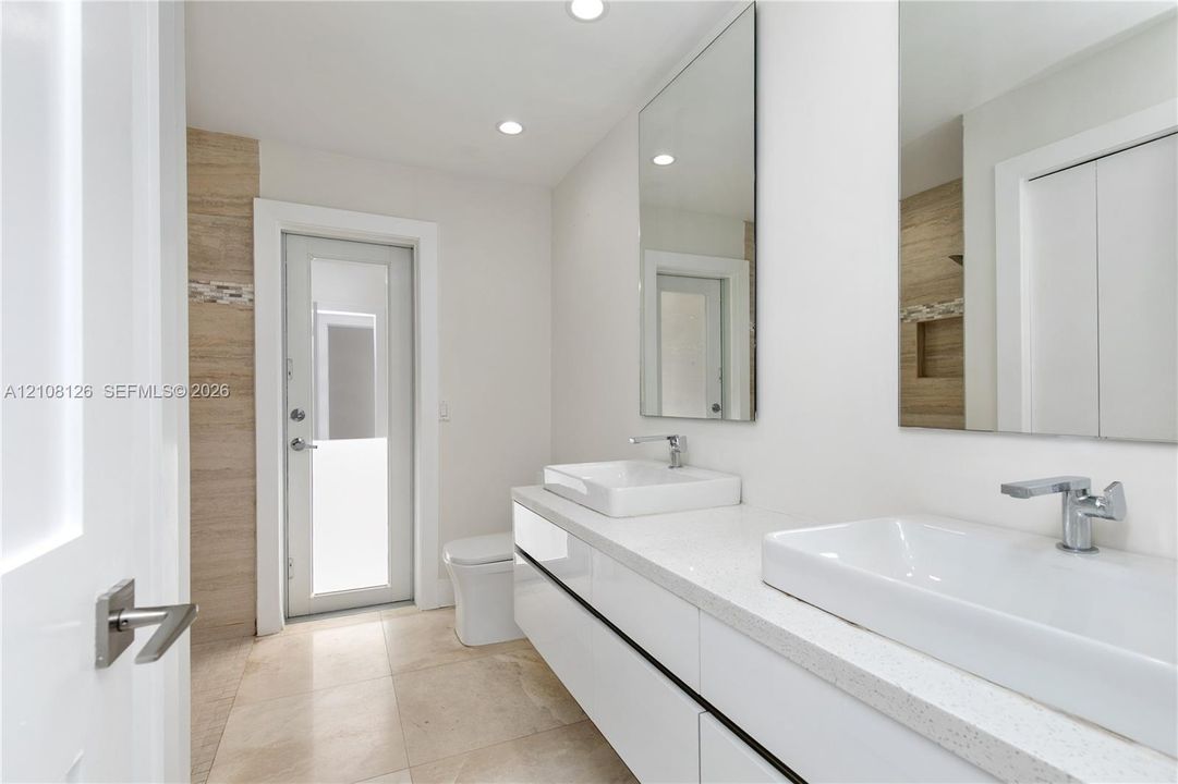 Floating double vanity with rectangular vessel sinks, quartz countertop, chrome faucets, and large-format tile flooring