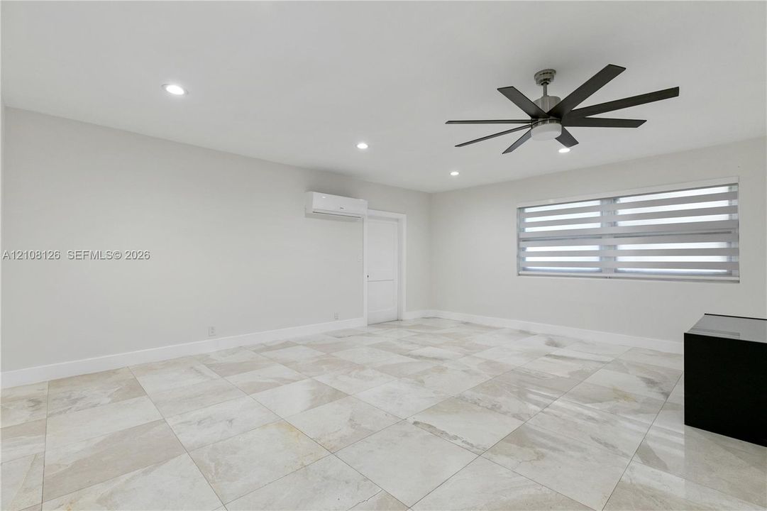 Interior space featuring large-format tile flooring, a multi-blade ceiling fan, recessed lighting, and a wall-mounted climate control unit