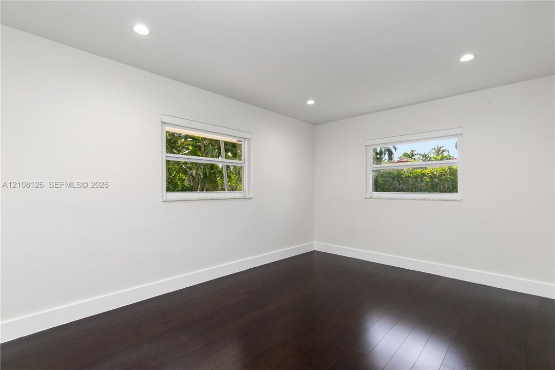 Interior room featuring dark wood-finish flooring, crisp white walls, and recessed ceiling lighting