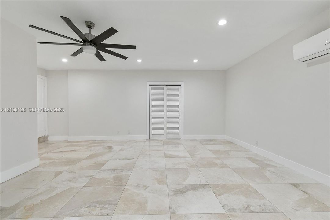 Large-format tile flooring, multi-blade ceiling fan, recessed lighting, and wall-mounted climate control unit
