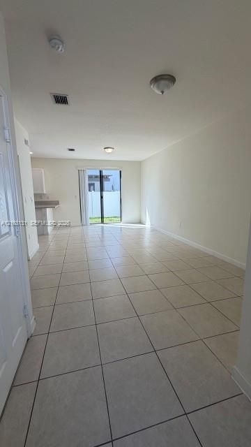 Open living area featuring neutral tile flooring, flush-mount lighting, and sliding glass doors