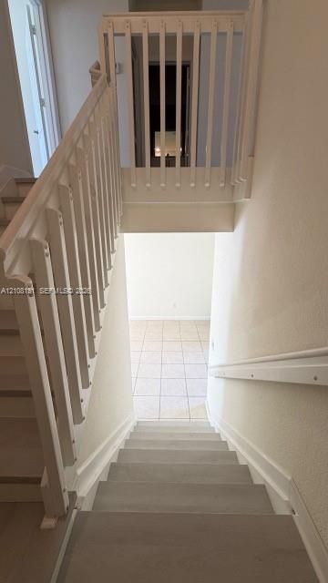 Staircase featuring wood-finish treads, white vertical balusters, and a wall-mounted handrail