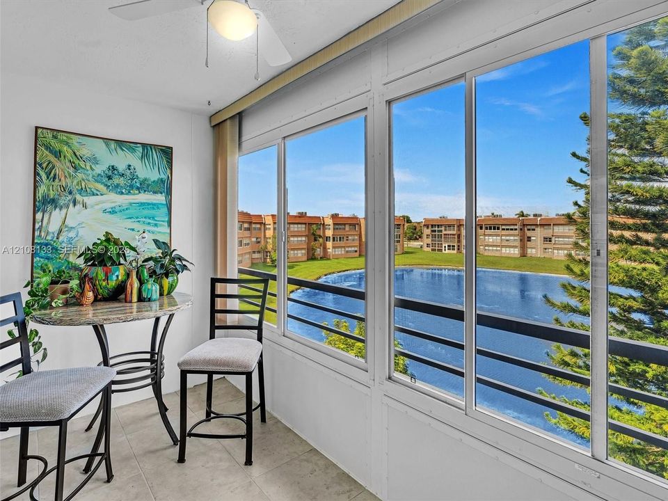Enclosed porch featuring tile flooring, ceiling fan, and large windows with horizontal railings overlooking a lake