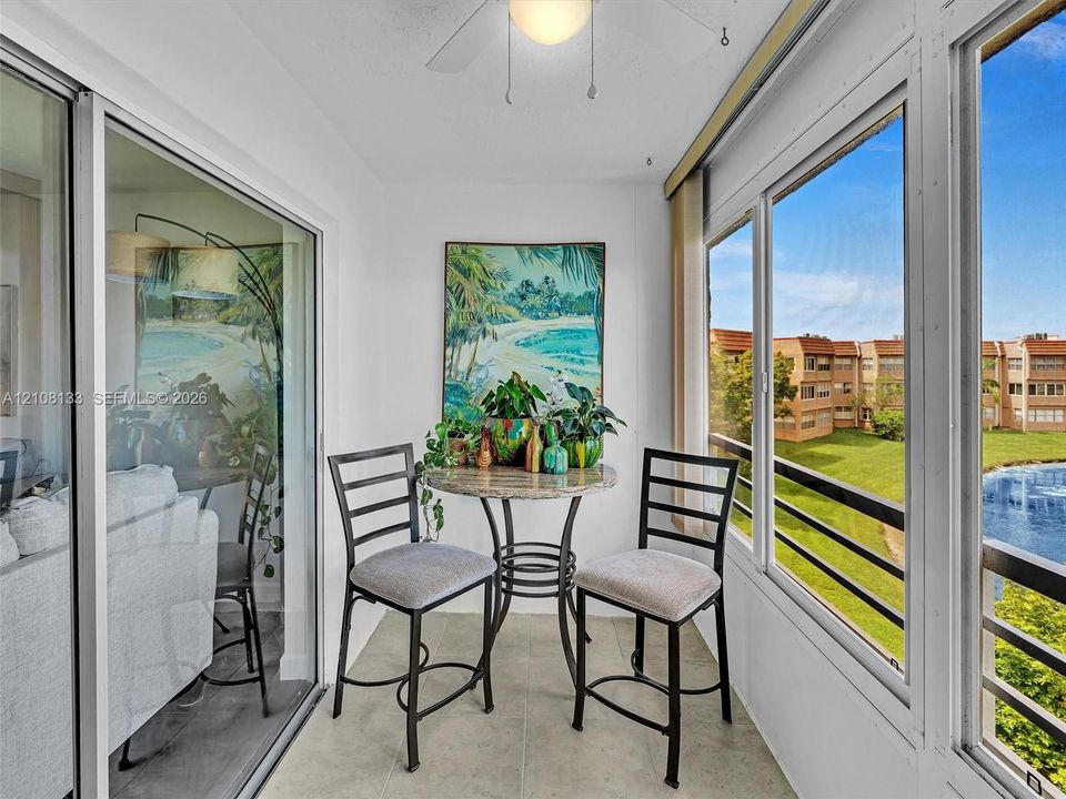 Enclosed sunroom featuring large-format tile flooring, oversized glass sliding doors, and floor-to-ceiling windows with a metal railing