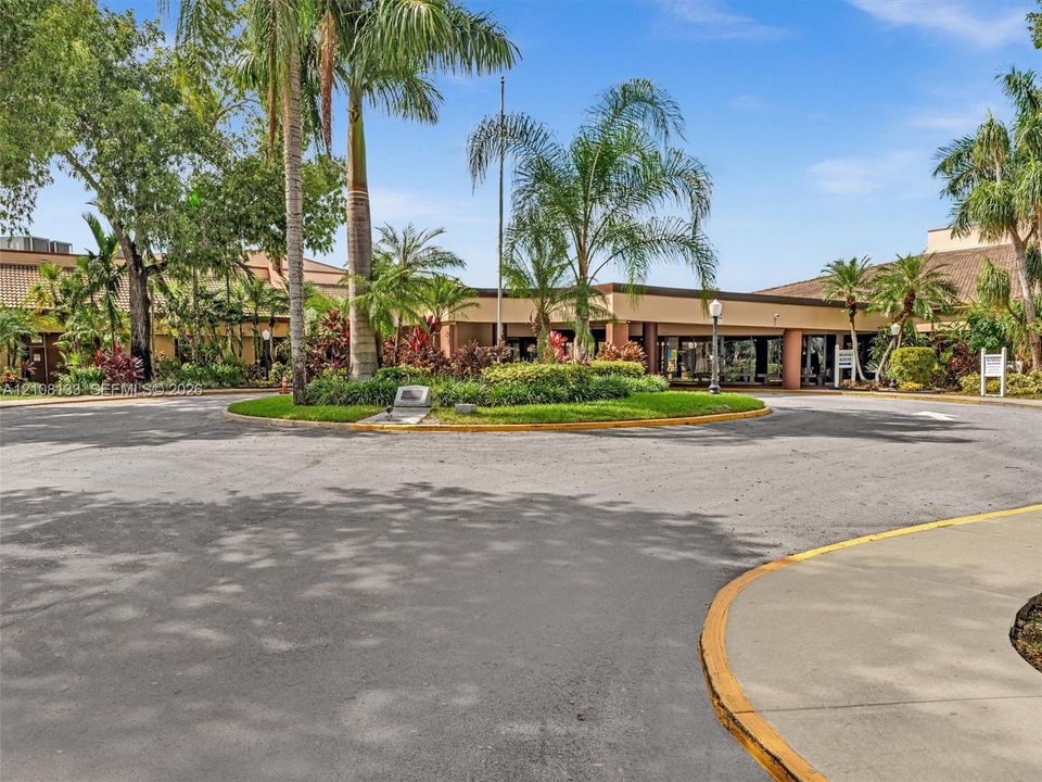 Circular asphalt driveway featuring a central island with mature palms and curated landscaping