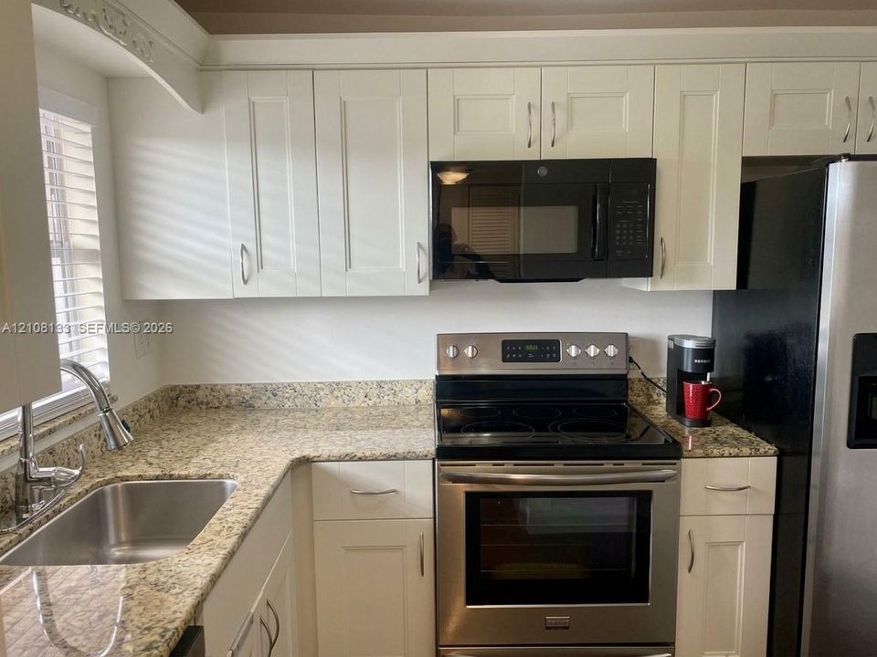 Kitchen featuring white shaker-style cabinetry, stone-finish countertops, stainless steel range, and an undermount sink with a gooseneck faucet