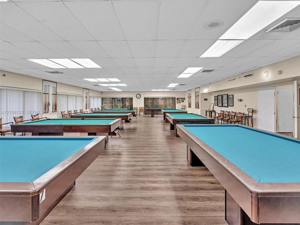 Expansive recreation room featuring wood-finish flooring, recessed lighting, and multiple window treatments