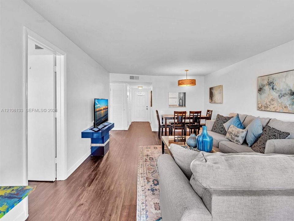 Open-concept living space featuring wood-finish flooring, recessed lighting, and a drum-style pendant light fixture